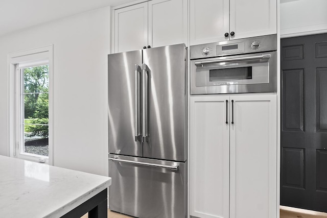 692 S Waukegan Rd, Lake Forest, IL 60045 - kitchen with appliances with stainless steel finishes, white cabinets, and light stone counters