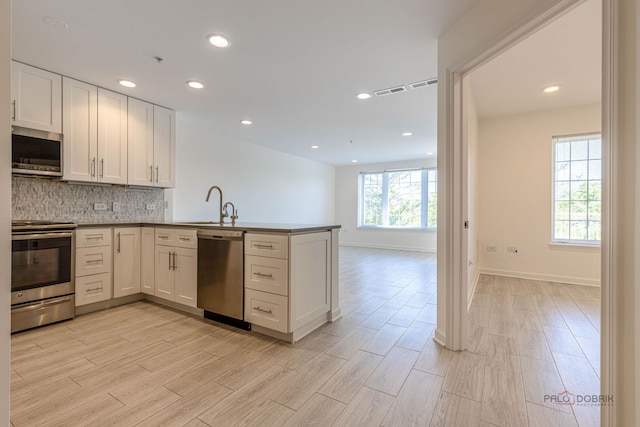 640 Robert York Ave Unit 306, Deerfield, IL 60015 - kitchen featuring stainless steel appliances, a peninsula, backsplash, light wood-style flooring, and white cabinets