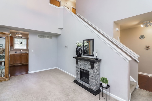 1769 Autumn Woods Ln, Romeoville, IL 60446 - unfurnished living room featuring stairs, carpet, a stone fireplace, a high ceiling, and a chandelier