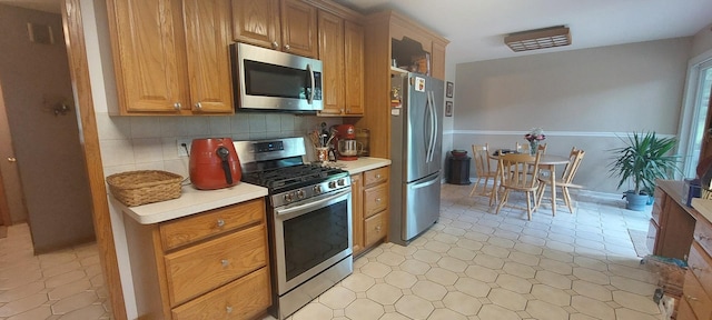 501 Hemlock Ln, Libertyville, IL 60048 - kitchen with stainless steel appliances, light countertops, decorative backsplash, and brown cabinetry