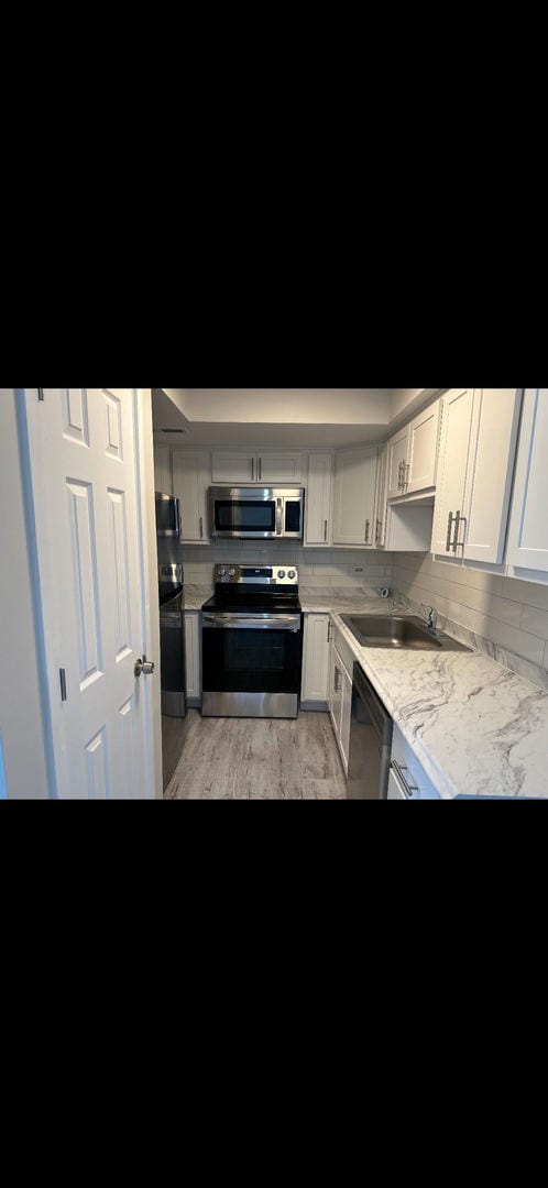 2237 175th St Unit 3A, Lansing, IL 60438 - kitchen with stainless steel appliances, light countertops, tasteful backsplash, light wood-type flooring, and white cabinets