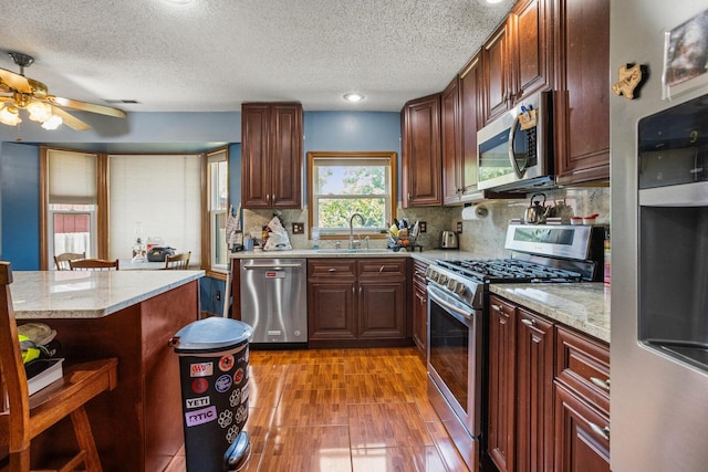 2612 Valkar Ln, Champaign, IL 61822 - kitchen with stainless steel appliances, light wood-type flooring, a ceiling fan, tasteful backsplash, and a textured ceiling
