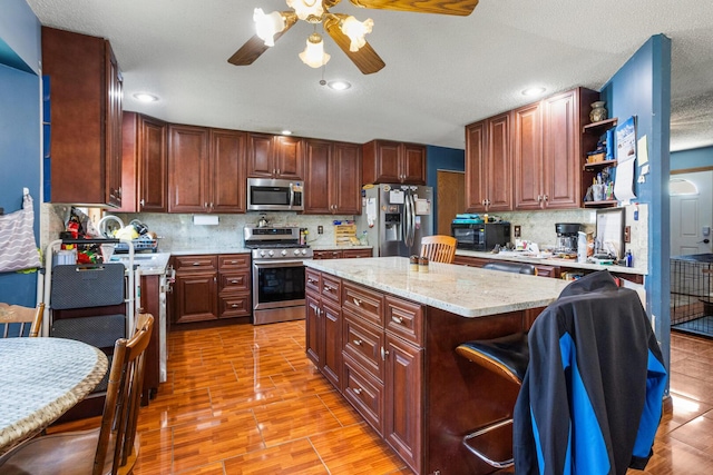 2612 Valkar Ln, Champaign, IL 61822 - kitchen featuring appliances with stainless steel finishes, ceiling fan, open shelves, tasteful backsplash, and a center island