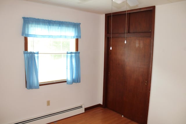 819 S W St, Earlville, IL 60518 - unfurnished bedroom with a baseboard heating unit, a closet, wood finished floors, and attic access