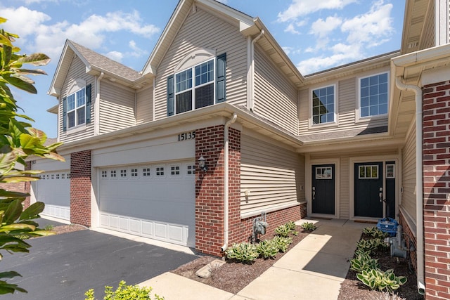 15135 W Quincy Cir, Manhattan, IL 60442 - view of exterior entry featuring an attached garage, brick siding, and driveway