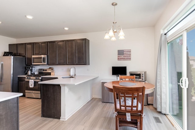 15135 W Quincy Cir, Manhattan, IL 60442 - kitchen featuring appliances with stainless steel finishes, light wood-style floors, light countertops, dark brown cabinetry, and a chandelier