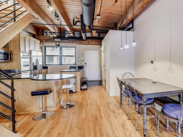 1740 N Marshfield Ave Unit 30, Chicago, IL 60622 - kitchen with stainless steel appliances, light wood-style floors, a wooden ceiling with exposed beams, dark countertops, and a peninsula