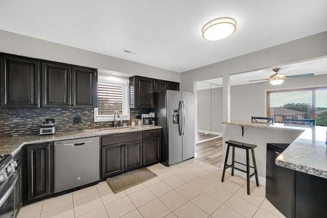 17824 Bernard Dr Unit 3D, Orland Park, IL 60467 - kitchen featuring stainless steel appliances, tasteful backsplash, ceiling fan, a breakfast bar area, and light stone countertops