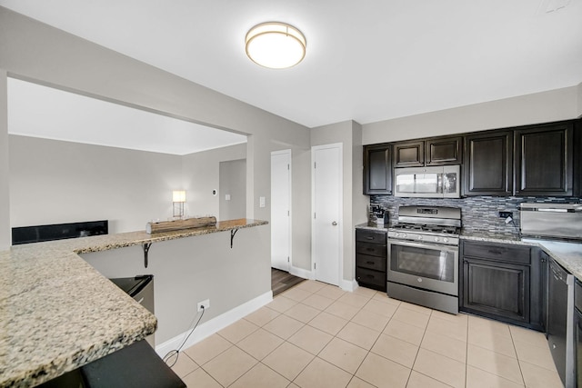 17824 Bernard Dr Unit 3D, Orland Park, IL 60467 - kitchen featuring appliances with stainless steel finishes, backsplash, light stone counters, and light tile patterned floors