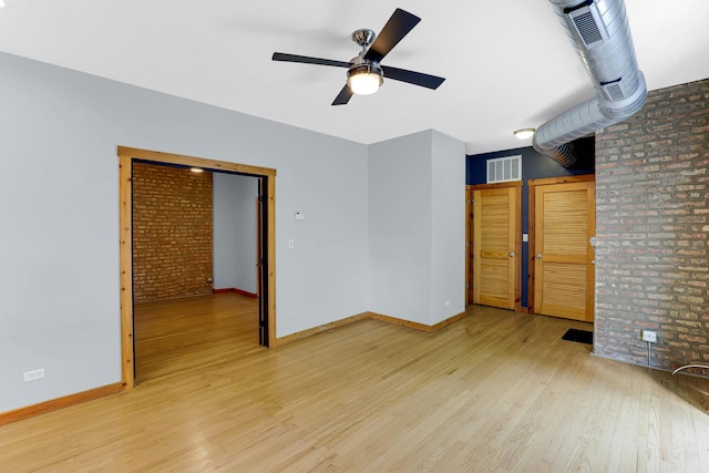1225 W Greenleaf Ave Unit 3E, Chicago, IL 60626 - unfurnished room featuring ceiling fan, wood finished floors, and brick wall