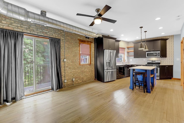 1225 W Greenleaf Ave Unit 3E, Chicago, IL 60626 - kitchen featuring stainless steel appliances, brick wall, light countertops, light wood-style flooring, and a kitchen island