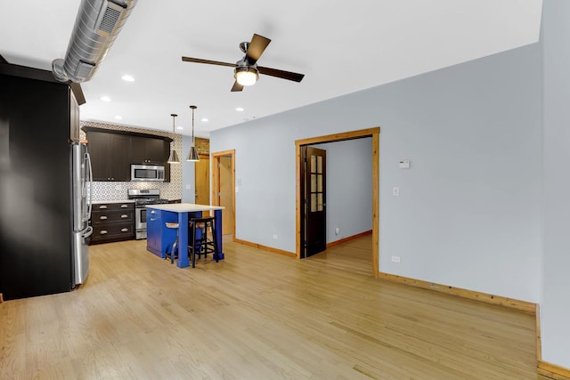1225 W Greenleaf Ave Unit 3E, Chicago, IL 60626 - kitchen with stainless steel appliances, a kitchen bar, decorative backsplash, a ceiling fan, and light wood finished floors