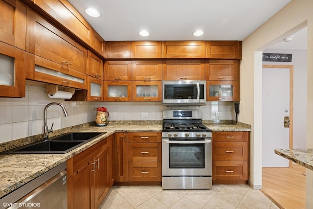 3300 N Carriageway Dr Unit 209, Arlington Heights, IL 60004 - kitchen featuring appliances with stainless steel finishes, brown cabinets, backsplash, light stone counters, and glass insert cabinets
