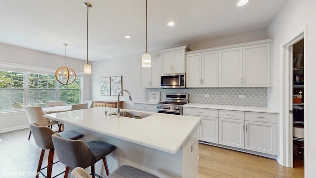 1517 128th St, Lemont, IL 60439 - kitchen featuring stainless steel appliances, tasteful backsplash, light wood-type flooring, a center island with sink, and a kitchen breakfast bar