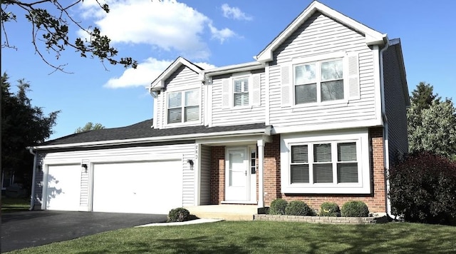 view of front of house featuring brick siding, driveway, a front yard, and a garage