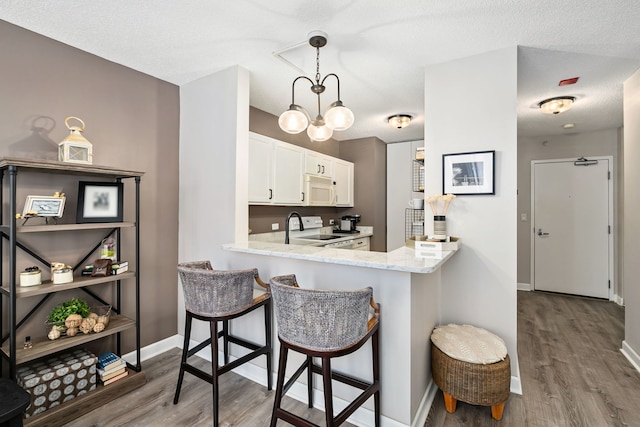 222 N Columbus Dr Unit 2204, Chicago, IL 60601 - kitchen with white appliances, wood finished floors, a kitchen breakfast bar, and white cabinetry