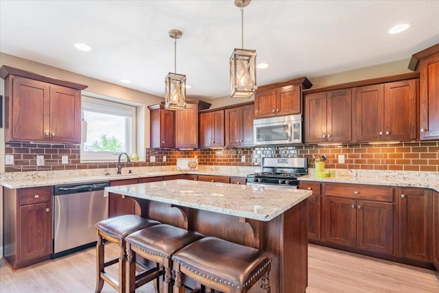 5108 Longfield Rd, Bloomington, IL 61705 - kitchen featuring stainless steel appliances, a kitchen island, light wood-style flooring, light stone counters, and recessed lighting