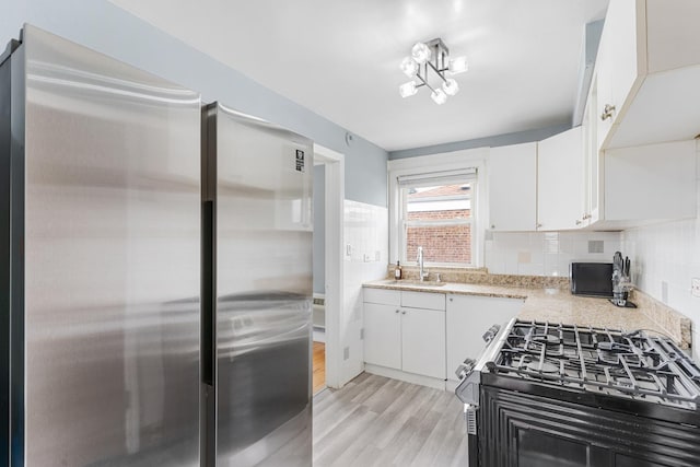 2204 S 9th Ave Unit 2, Broadview, IL 60155 - kitchen featuring freestanding refrigerator, gas range, light wood-type flooring, white cabinetry, and tasteful backsplash