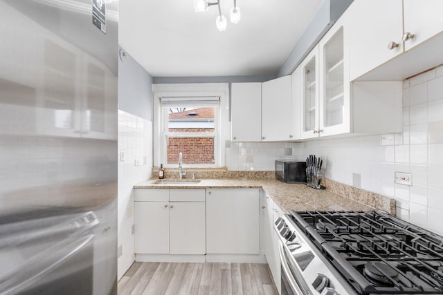 2204 S 9th Ave Unit 2, Broadview, IL 60155 - kitchen with stainless steel range with gas cooktop, tasteful backsplash, white cabinetry, glass insert cabinets, and light wood finished floors