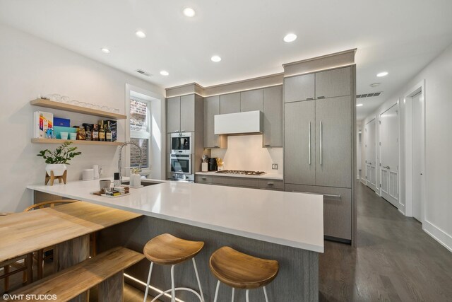 2814 W N Ave Unit 2W, Chicago, IL 60647 - kitchen with gray cabinetry, gas cooktop, a peninsula, a breakfast bar area, and dark wood-style flooring