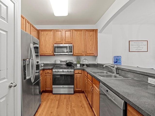 6079 Delaney Dr, Hoffman Estates, IL 60192 - kitchen with appliances with stainless steel finishes, light wood finished floors, dark countertops, arched walkways, and brown cabinetry