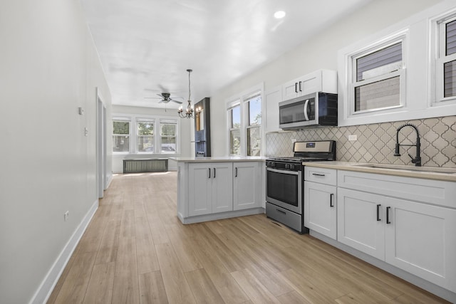 1332 Euclid Ave, Berwyn, IL 60402 - kitchen with appliances with stainless steel finishes, a peninsula, a chandelier, white cabinetry, and tasteful backsplash