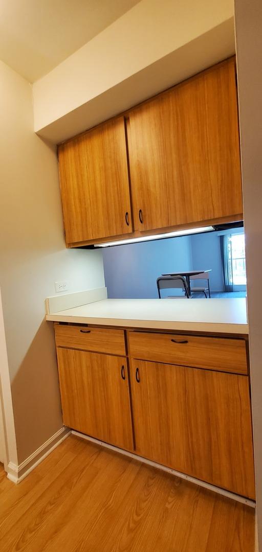 5100 Carriageway Dr Unit 305-2, Rolling Meadows, IL 60008 - kitchen featuring brown cabinets, light countertops, and light wood-type flooring