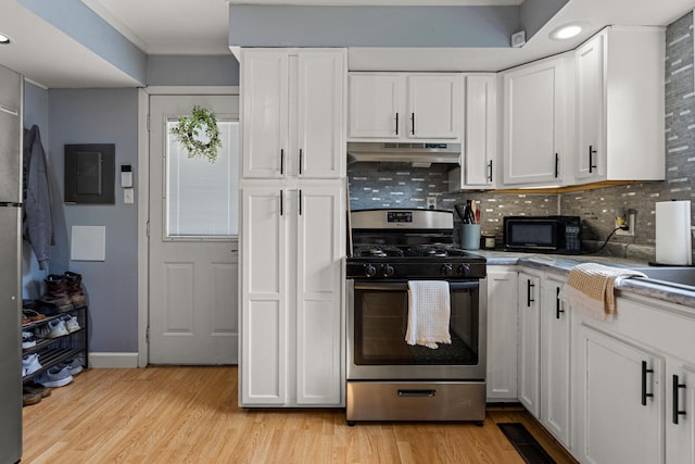 405 N Vorcey St, Tolono, IL 61880 - kitchen with stainless steel gas stove, under cabinet range hood, white cabinetry, light wood-style floors, and tasteful backsplash