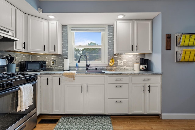 405 N Vorcey St, Tolono, IL 61880 - kitchen featuring gas stove, black microwave, white cabinets, backsplash, and light wood-style floors