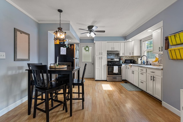 405 N Vorcey St, Tolono, IL 61880 - kitchen with stainless steel appliances, light wood-style flooring, white cabinets, tasteful backsplash, and crown molding