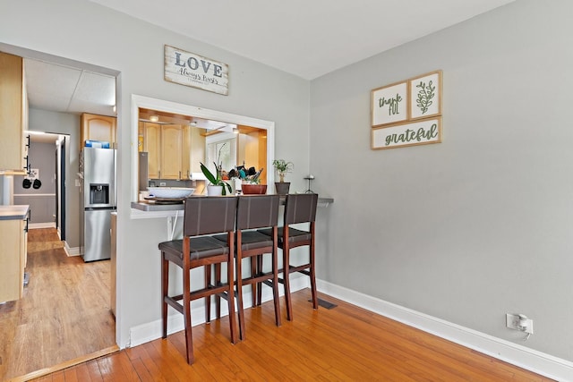 2250 Corona Rd, Waukegan, IL 60087 - kitchen with stainless steel fridge with ice dispenser, light wood-style flooring, a breakfast bar, and a peninsula