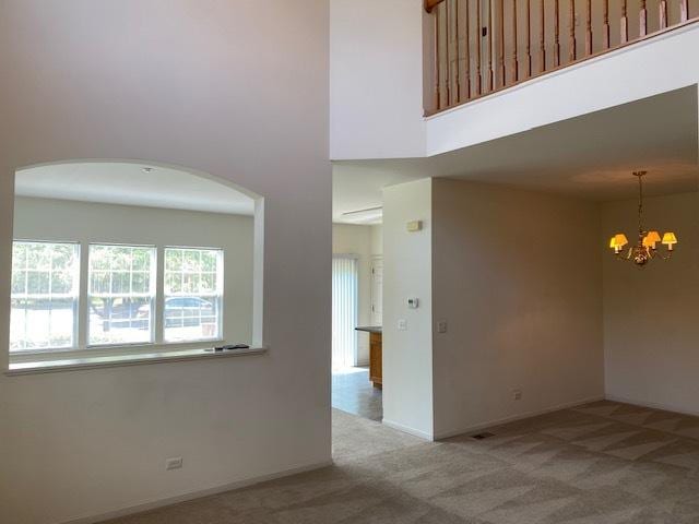 1830 Maureen Dr, Hoffman Estates, IL 60192 - empty room featuring carpet flooring, a towering ceiling, a chandelier, and arched walkways