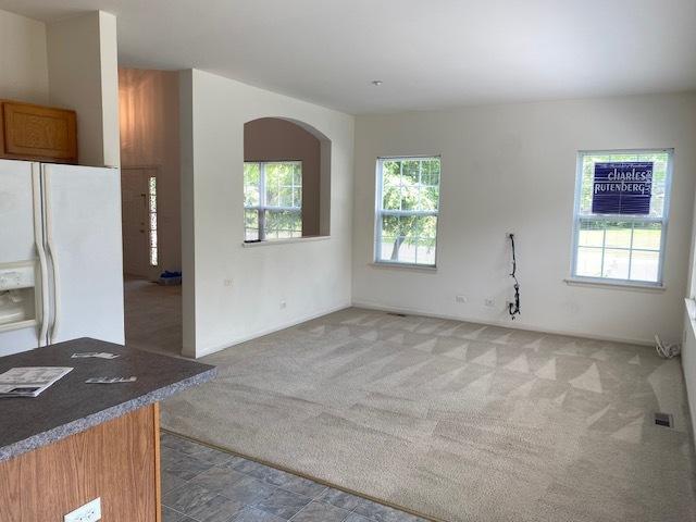 1830 Maureen Dr, Hoffman Estates, IL 60192 - kitchen featuring white refrigerator with ice dispenser, light carpet, brown cabinetry, and arched walkways