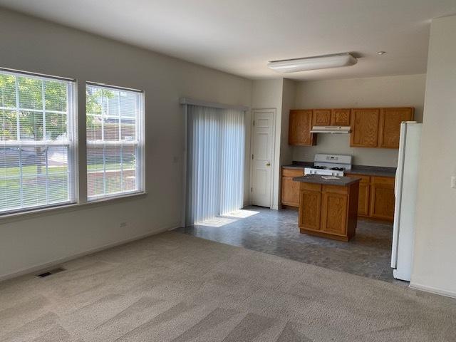 1830 Maureen Dr, Hoffman Estates, IL 60192 - kitchen with white appliances, under cabinet range hood, brown cabinetry, and healthy amount of natural light