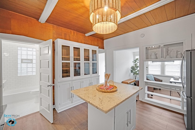 1659 N Francisco Ave, Chicago, IL 60647 - kitchen with a wooden ceiling with exposed beams, freestanding refrigerator, white cabinets, light stone counters, and a kitchen island