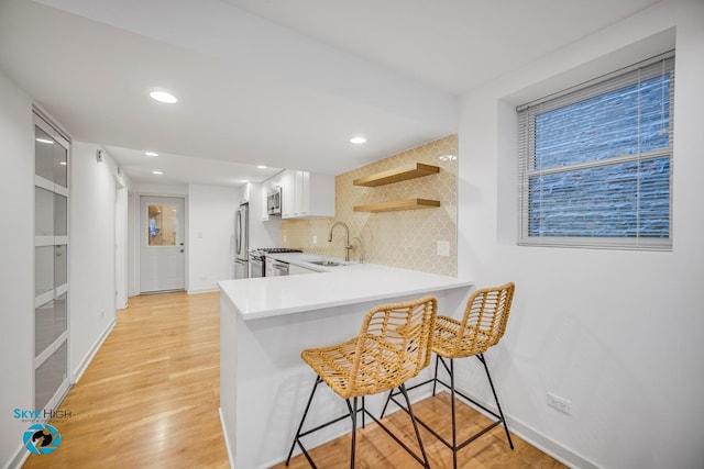 1659 N Francisco Ave, Chicago, IL 60647 - kitchen featuring stainless steel appliances, open shelves, tasteful backsplash, a kitchen breakfast bar, and light wood-type flooring