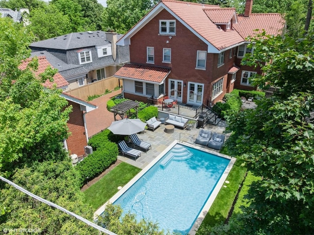 938 Edgemere Ct, Evanston, IL 60202 - back of property with outdoor lounge area, a tile roof, a patio, brick siding, and an outdoor pool