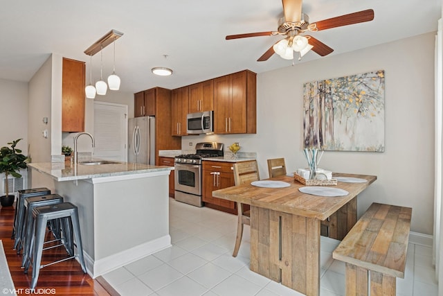 926 Bromley Pl, Northbrook, IL 60062 - kitchen with stainless steel appliances, a peninsula, brown cabinetry, a ceiling fan, and a kitchen breakfast bar
