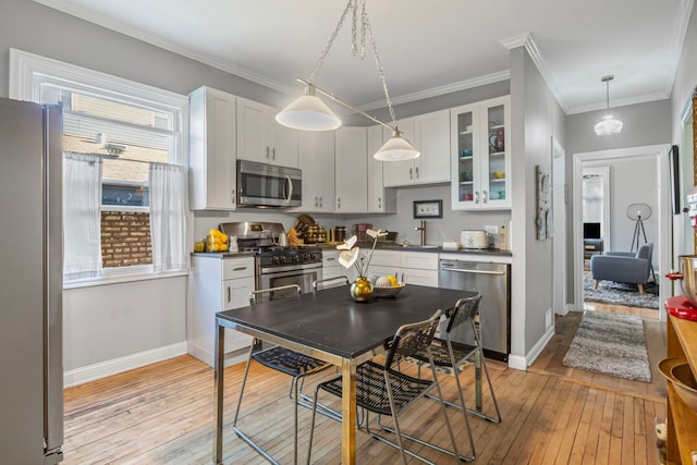 2119 N Karlov Ave, Chicago, IL 60639 - kitchen with stainless steel appliances, light wood finished floors, dark countertops, white cabinets, and ornamental molding
