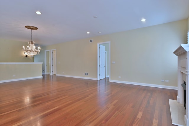121 Rose Dr, Bloomingdale, IL 60108 - unfurnished living room with a fireplace with raised hearth, a chandelier, wood finished floors, and recessed lighting