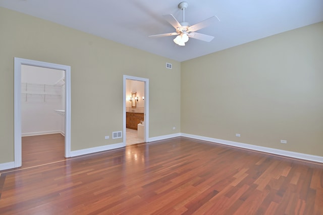 121 Rose Dr, Bloomingdale, IL 60108 - unfurnished bedroom featuring wood finished floors, a spacious closet, a closet, ceiling fan, and ensuite bath