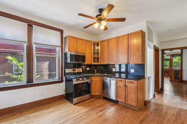 2638 W Rice St Unit 2S, Chicago, IL 60622 - kitchen with appliances with stainless steel finishes, light wood-style floors, decorative backsplash, dark countertops, and ceiling fan
