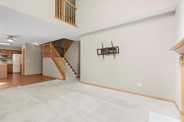 179 Briarcliff Ct, Romeoville, IL 60446 - unfurnished living room featuring light colored carpet, stairs, a ceiling fan, and a towering ceiling