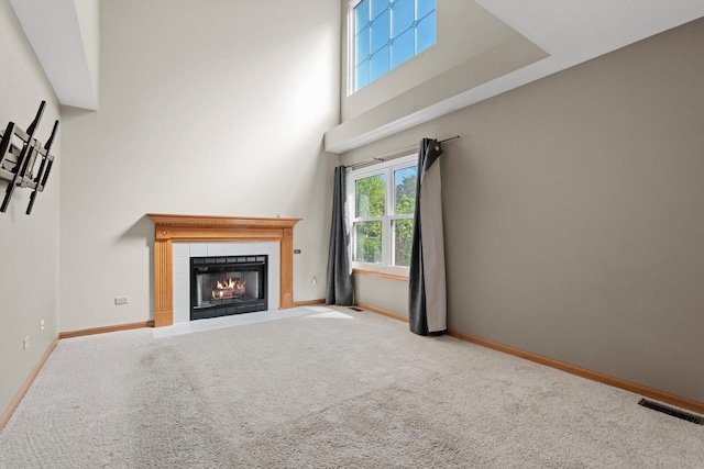 179 Briarcliff Ct, Romeoville, IL 60446 - unfurnished living room featuring carpet floors, a tiled fireplace, and a high ceiling