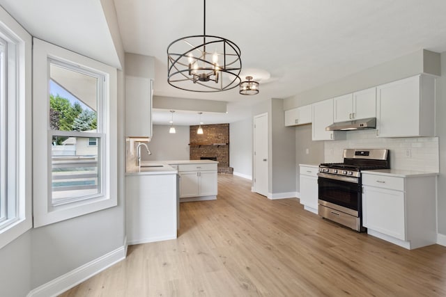 6282 Schaumburg Ln, Roscoe, IL 61073 - kitchen with stainless steel gas range oven, under cabinet range hood, backsplash, a chandelier, and light countertops