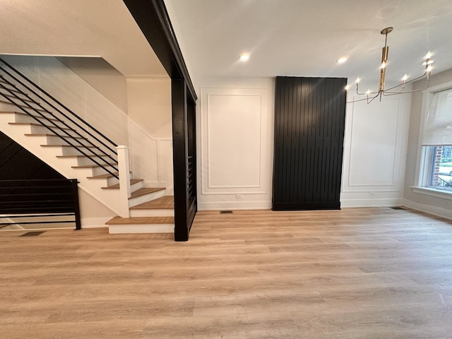 4409 S Prairie Ave, Chicago, IL 60653 - unfurnished living room with a decorative wall, a chandelier, light wood-type flooring, stairs, and recessed lighting
