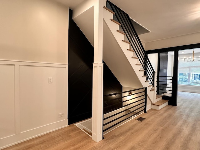 4409 S Prairie Ave, Chicago, IL 60653 - stairway featuring a decorative wall, wood finished floors, and wainscoting