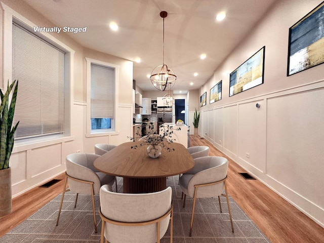 4409 S Prairie Ave, Chicago, IL 60653 - dining room featuring a decorative wall, wood finished floors, a chandelier, recessed lighting, and a wainscoted wall