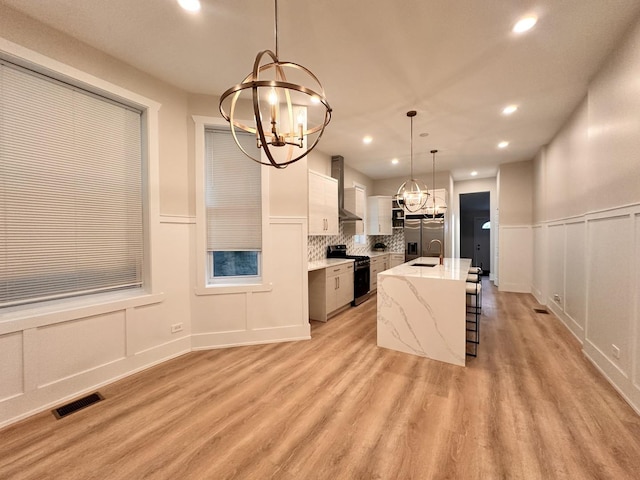 4409 S Prairie Ave, Chicago, IL 60653 - kitchen with stove, a chandelier, wall chimney range hood, stainless steel fridge with ice dispenser, and a decorative wall