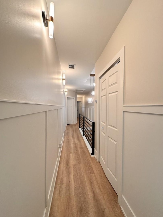 4409 S Prairie Ave, Chicago, IL 60653 - hall featuring light wood-style floors, a wainscoted wall, and a decorative wall